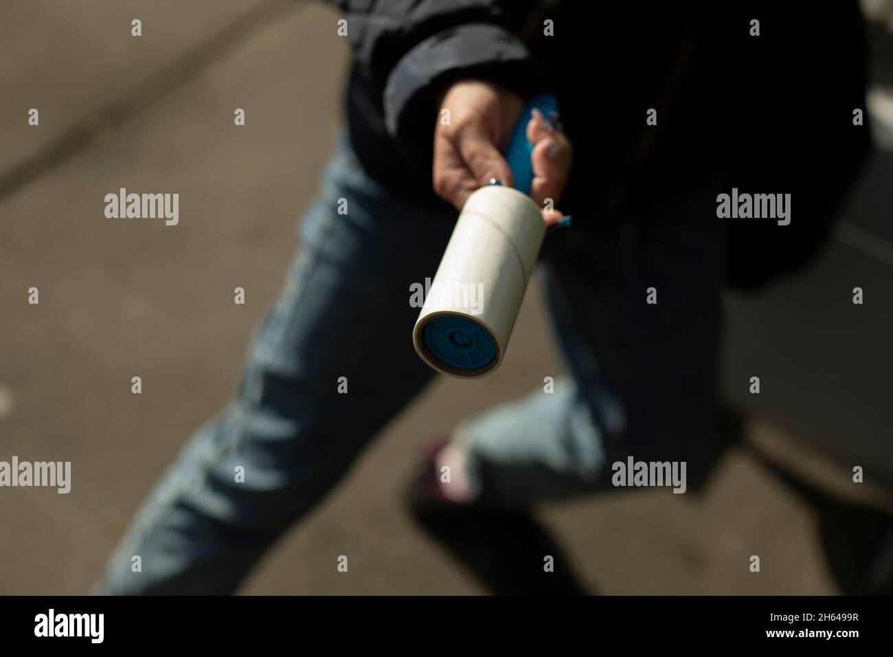 Nastro adesivo per rimuovere la lana dai vestiti. Strumento per la pulizia  dei vestiti dai capelli. La ragazza tiene in mano un oggetto per rimuovere  lo sporco dalle cose Foto stock -