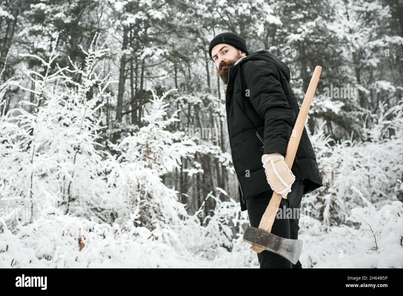 Uomo lumberjack con ascia. Congelamento, scatto a freddo. Uomo bearded con  ascia in foresta nevosa Foto stock - Alamy