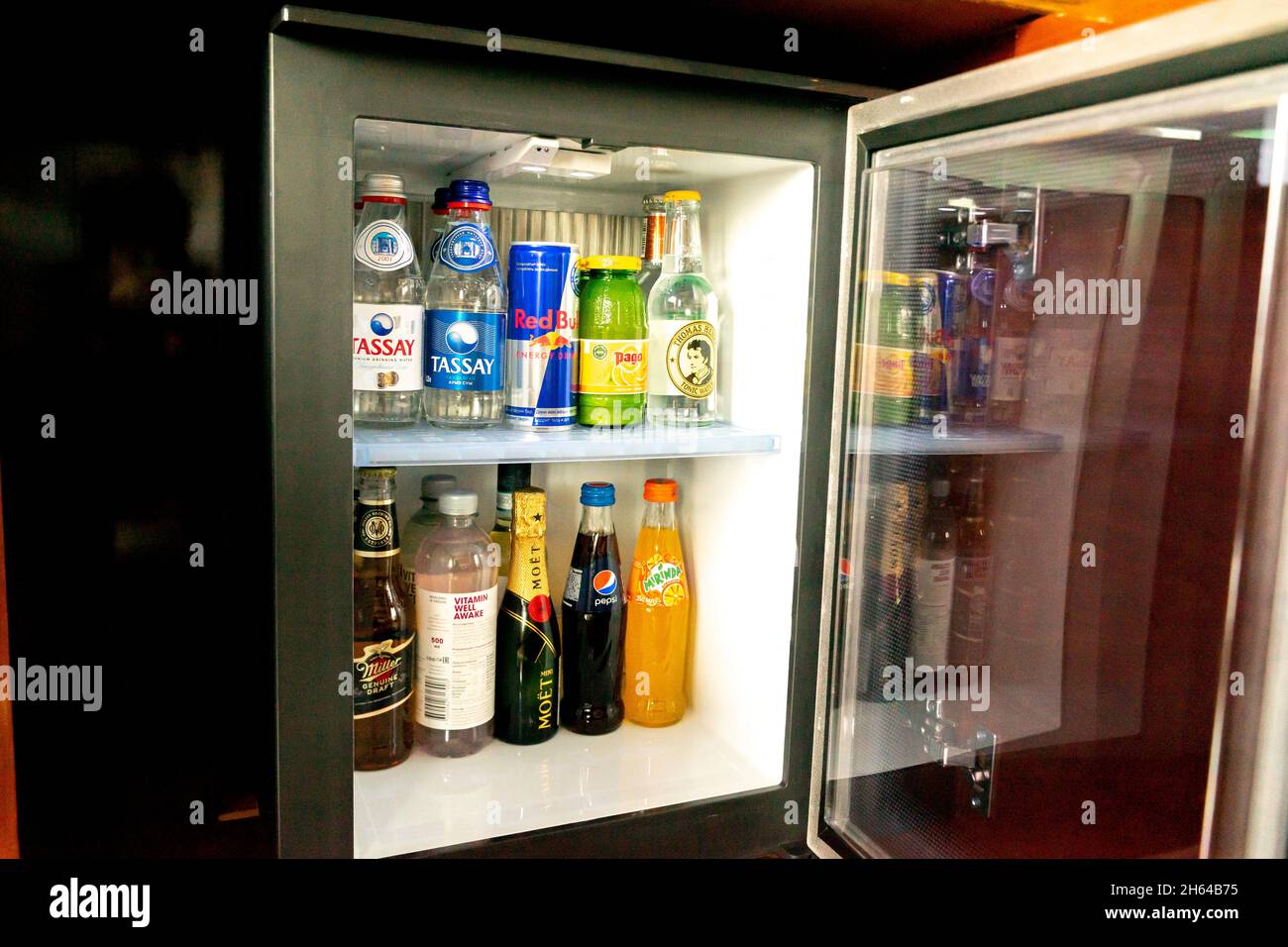 Bottiglie di acqua e bibite analcoliche, bevande energetiche, coke, red bull in un piccolo frigorifero tipico del minibar con una porta aperta in un hotel Foto Stock