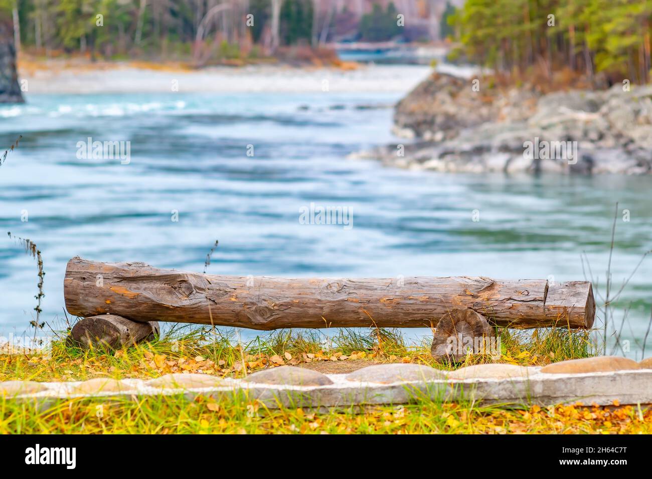 vista di un grande tronco di albero non trattato nella forma di una panchina per godere il paesaggio con un bel fiume tortuoso in un luogo pittoresco resort Foto Stock
