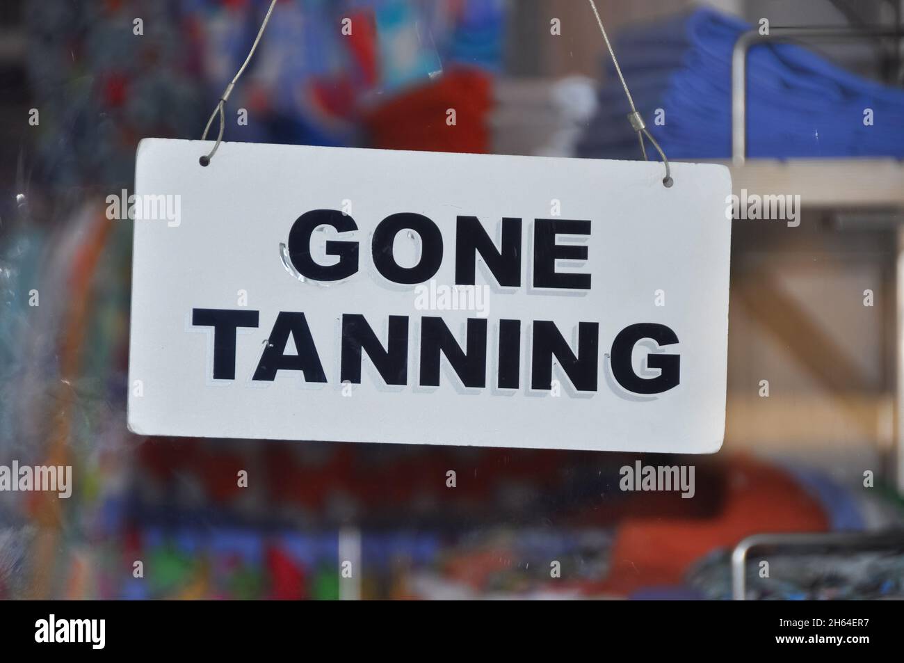Primo piano di un cartello sullo sportello di vetro di un negozio che informa i clienti che il negozio è chiuso (temporaneamente) con il messaggio -Gone abbronzatura- Foto Stock