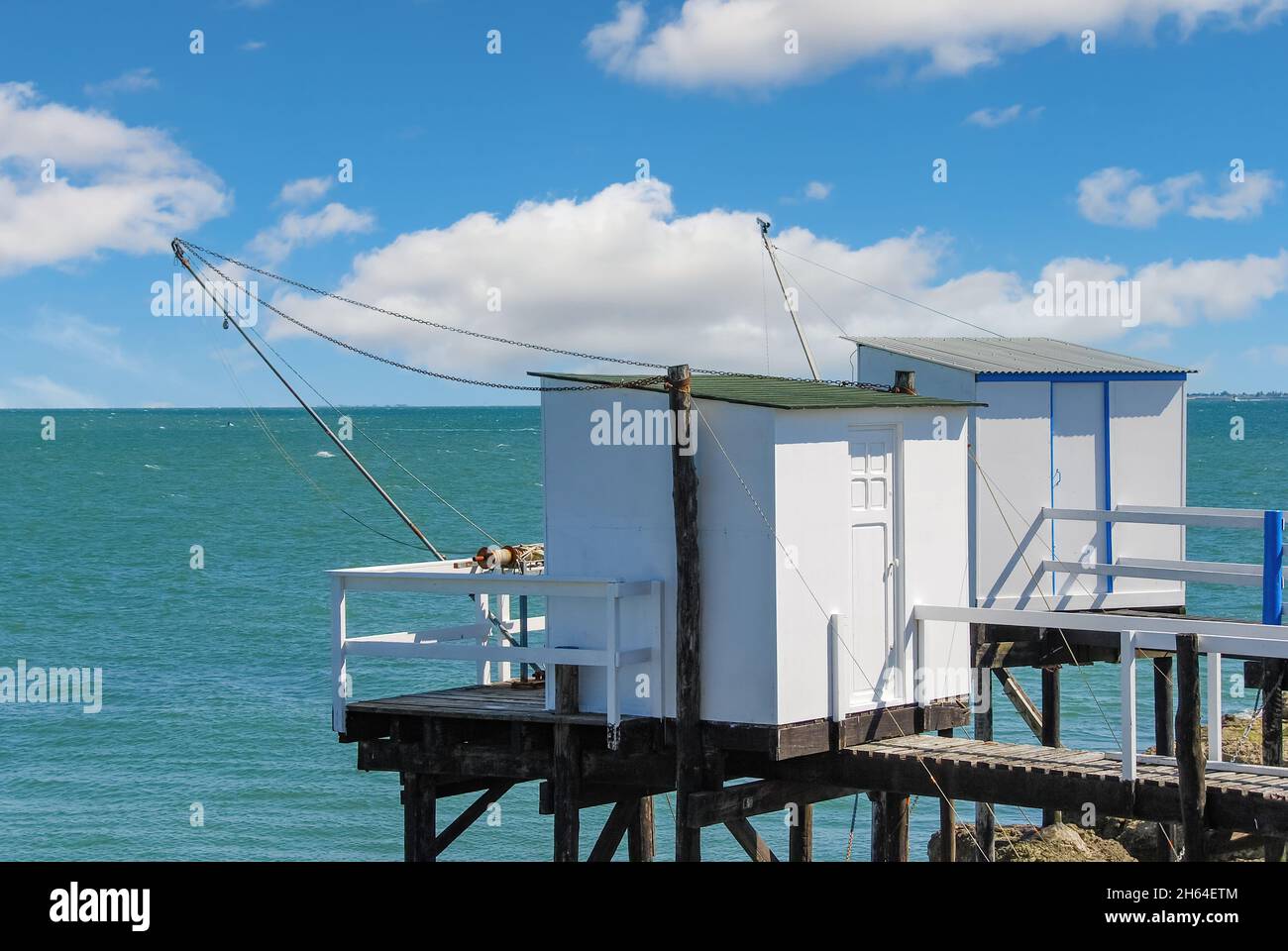 Vista delle tradizionali capanne da pesca su palafitte con carrelets sospesi (reti da pesca) lungo l'estuario della Gironda vicino Boardeax, Francia con Oceano Atlantico Foto Stock