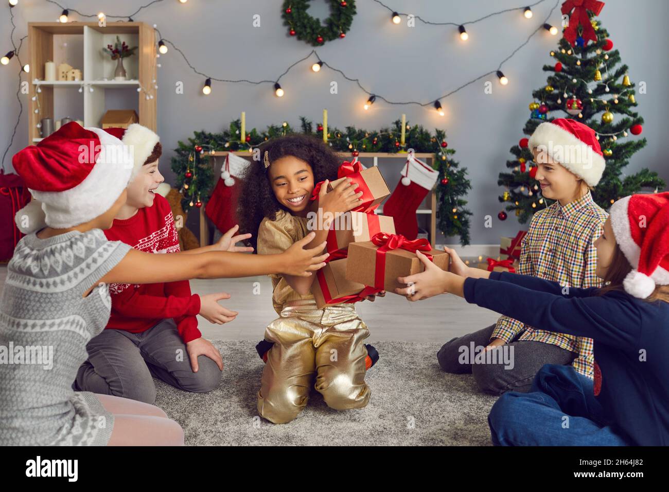 Gruppo di bambini ridenti felici che danno regali di Natale alla loro sorella o amico Foto Stock