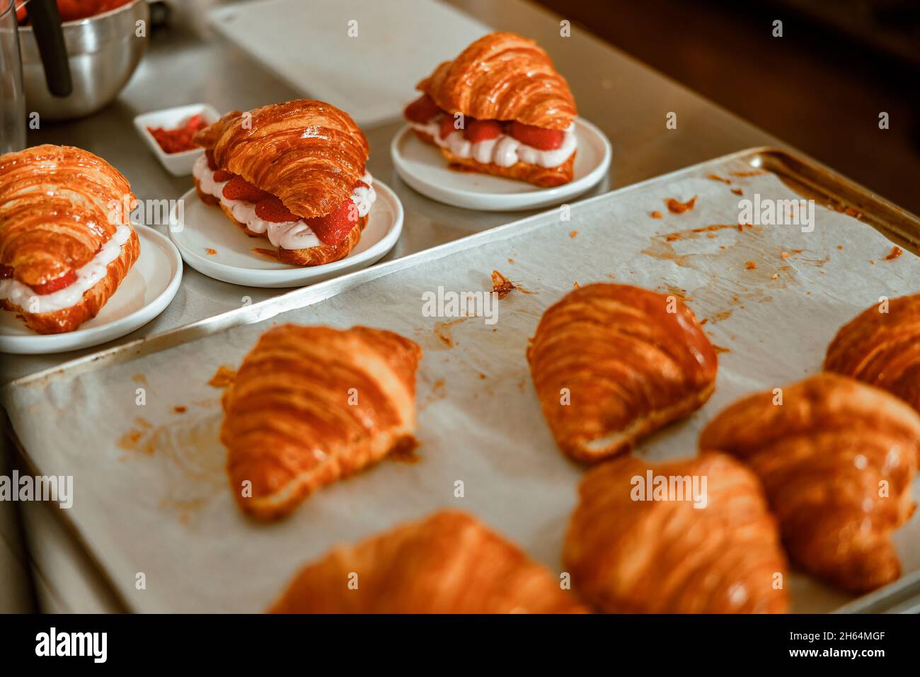 Croissant con panna e fragole fresche su tavolo in metallo in negozio Foto Stock