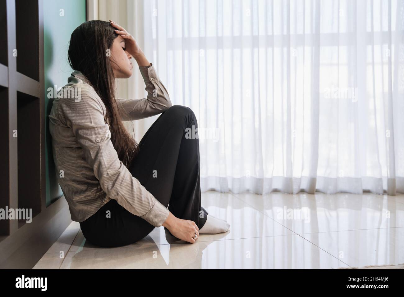 Donna latina seduta sul pavimento si sente infelice da problemi personali, rottura o rovinato matrimonio, gravidanza non volenteroso rammarico per decisione aborto, chro Foto Stock