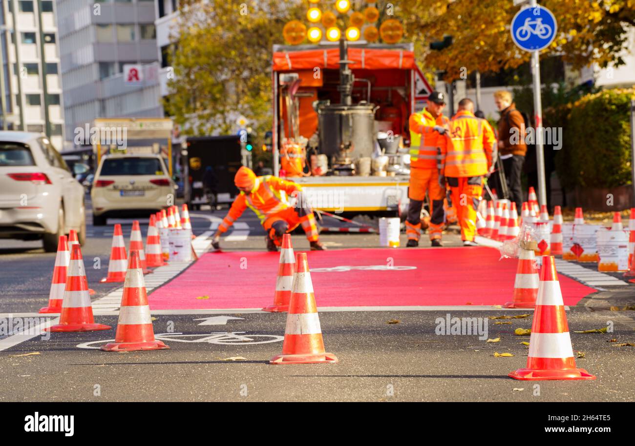 10 novembre 2021, Hessen, Francoforte sul meno: I lavoratori hanno tracciato una pista ciclabile con vernice rossa. In Gartenstraße/Walter-Kolb-Straße un percorso ciclabile è contrassegnato con vernice rossa. Foto: Andreas Arnold/dpa Foto Stock