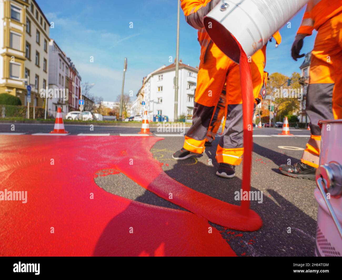 10 novembre 2021, Hessen, Francoforte sul meno: Un lavoratore versa la vernice rossa per il percorso ciclistico sulla superficie di marcatura. Un percorso ciclabile è contrassegnato con vernice rossa in Gartenstraße/Walter-Kolb-Straße. Foto: Andreas Arnold/dpa Foto Stock