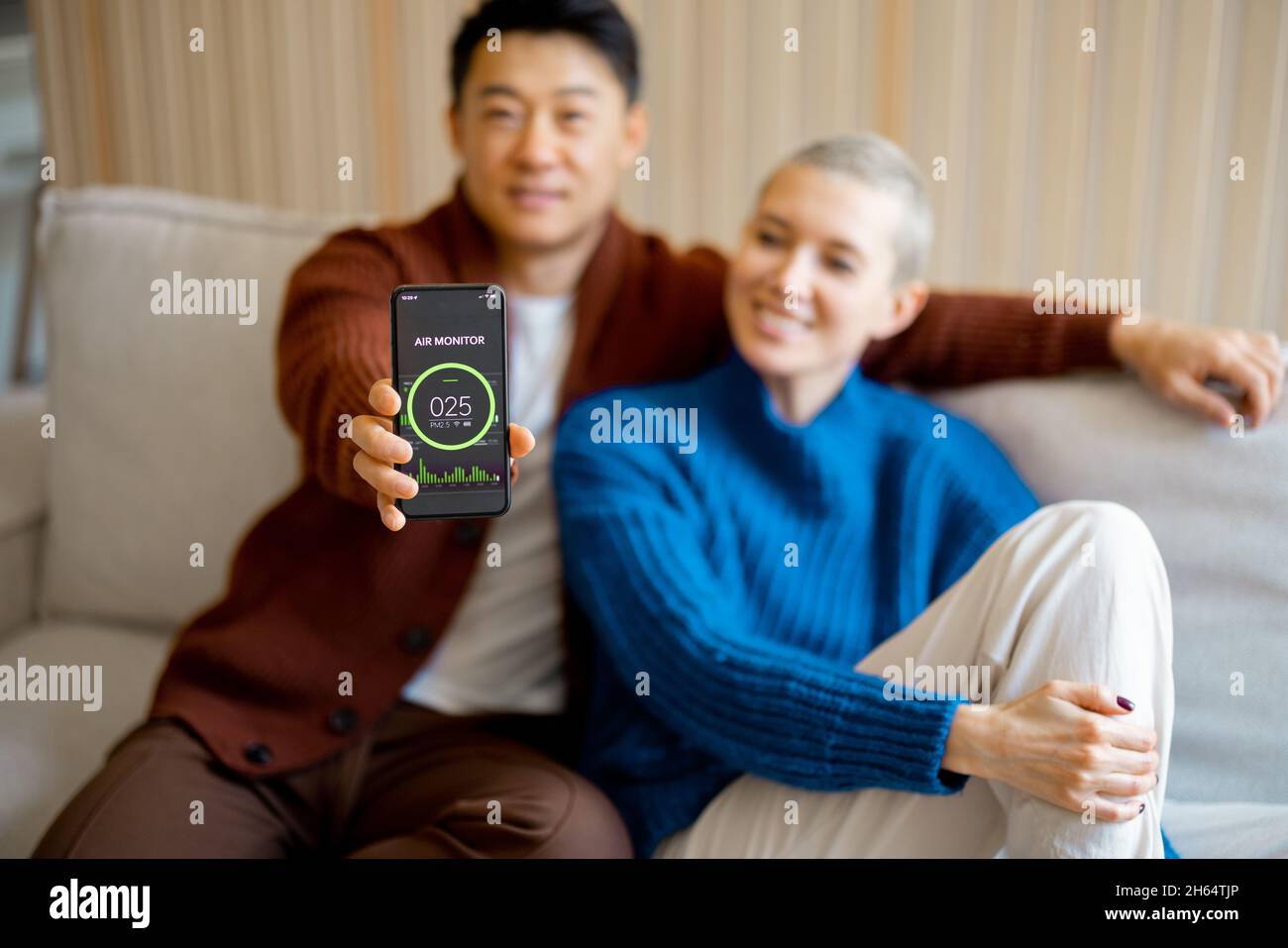 Uomo che mostra l'app per l'aria condizionata domestica sullo smartphone Foto Stock