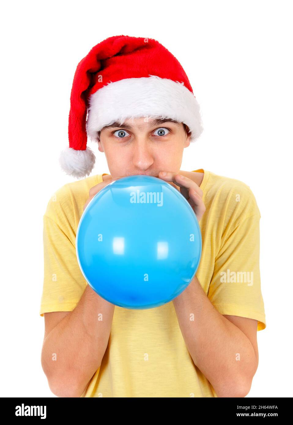 Giovane uomo a Santa Hat gonfiare una palloncino blu isolato sullo sfondo bianco Foto Stock