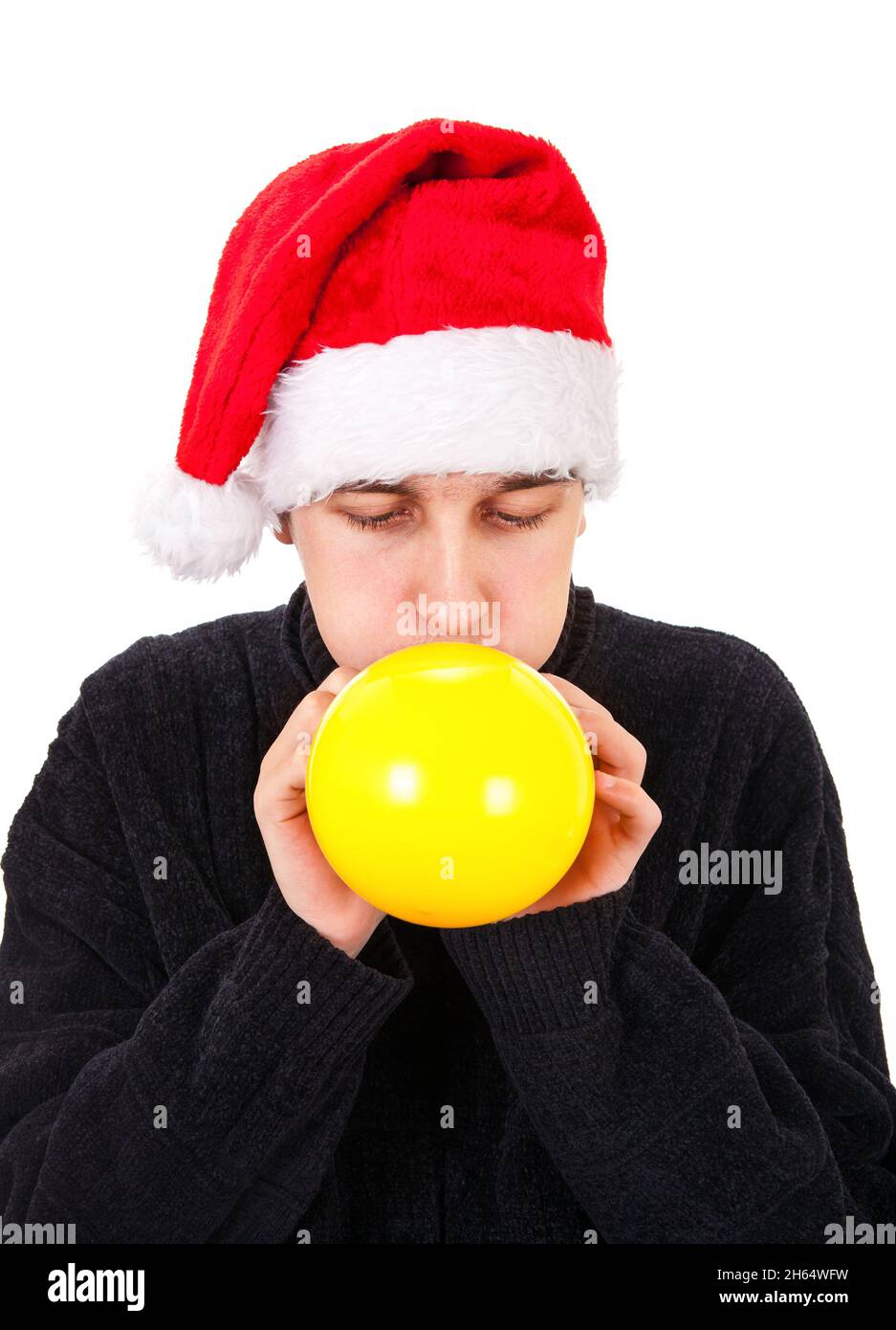 Giovane uomo a Santa Hat gonfiare un pallone giallo isolato sullo sfondo bianco Foto Stock