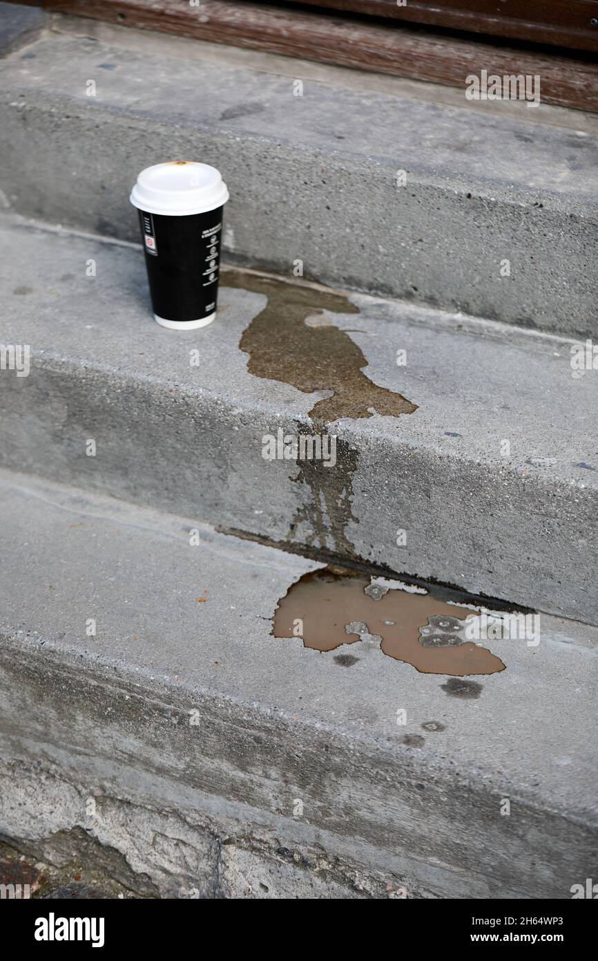 Tazza di caffè di carta e caffè versato su scale di cemento Foto Stock