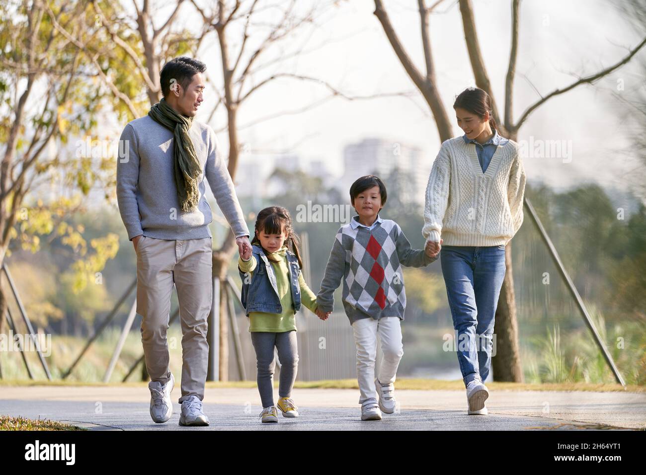 happy famiglia asiatica con due bambini che si prendono una passeggiata all'aperto nel parco della città Foto Stock