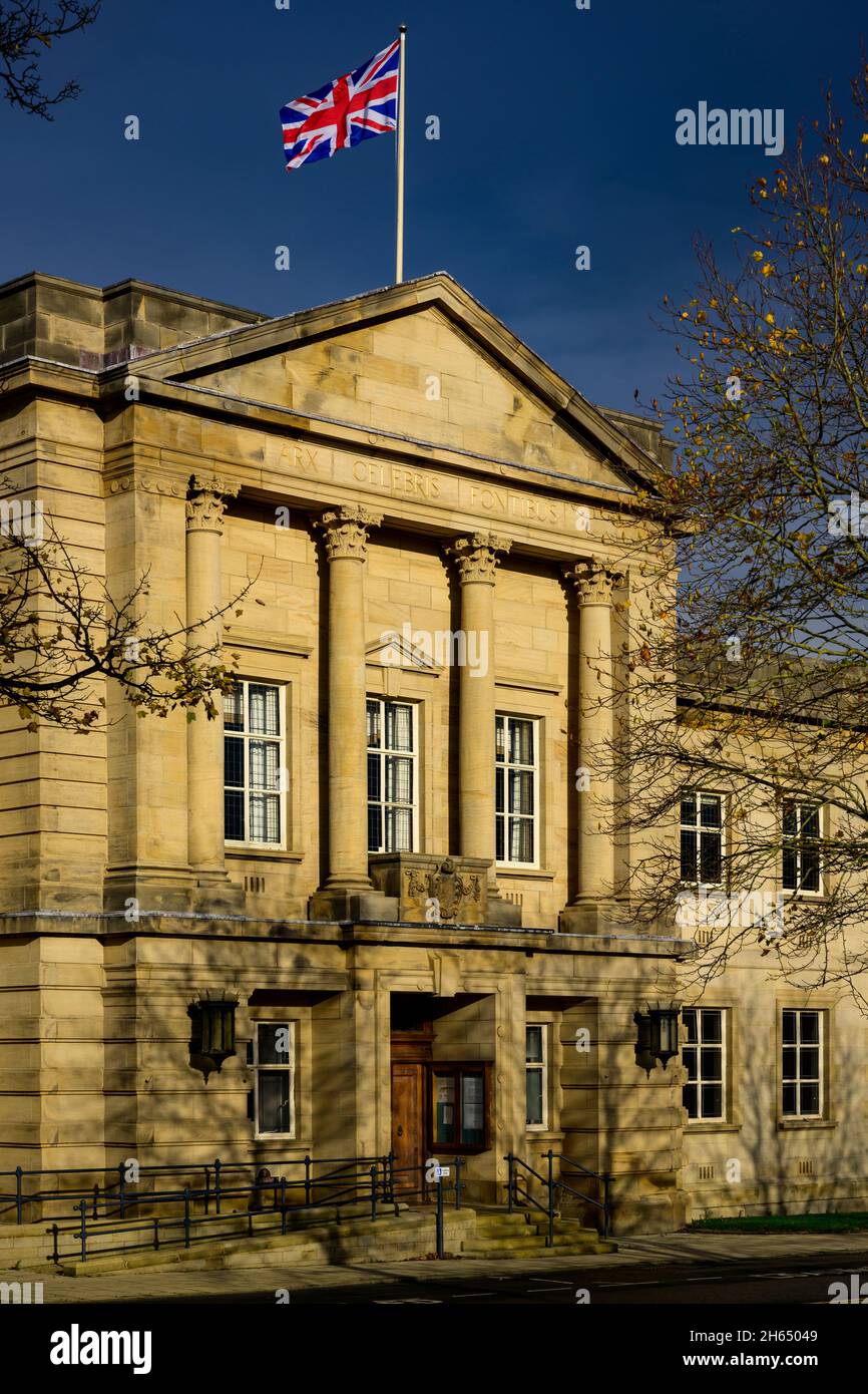 Bandiera Union Jack che sorvola gli uffici del consiglio di Harrogate (flagpole, esterno dell'edificio illuminato dal sole, cielo blu scuro) - Crescent Gardens, Yorkshire Inghilterra, Regno Unito. Foto Stock