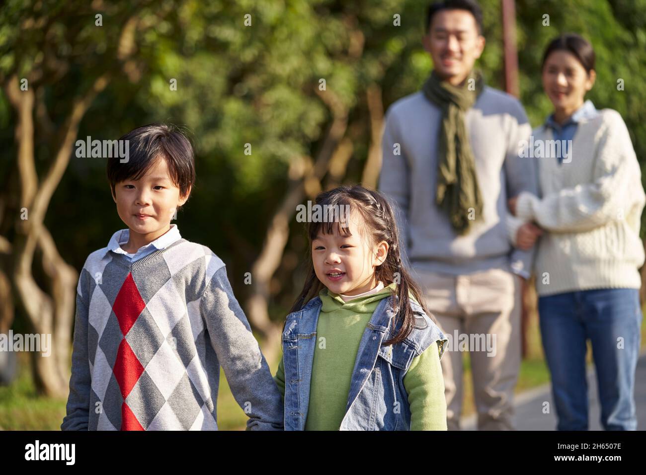 happy famiglia asiatica con due bambini che si prendono una passeggiata all'aperto nel parco della città Foto Stock