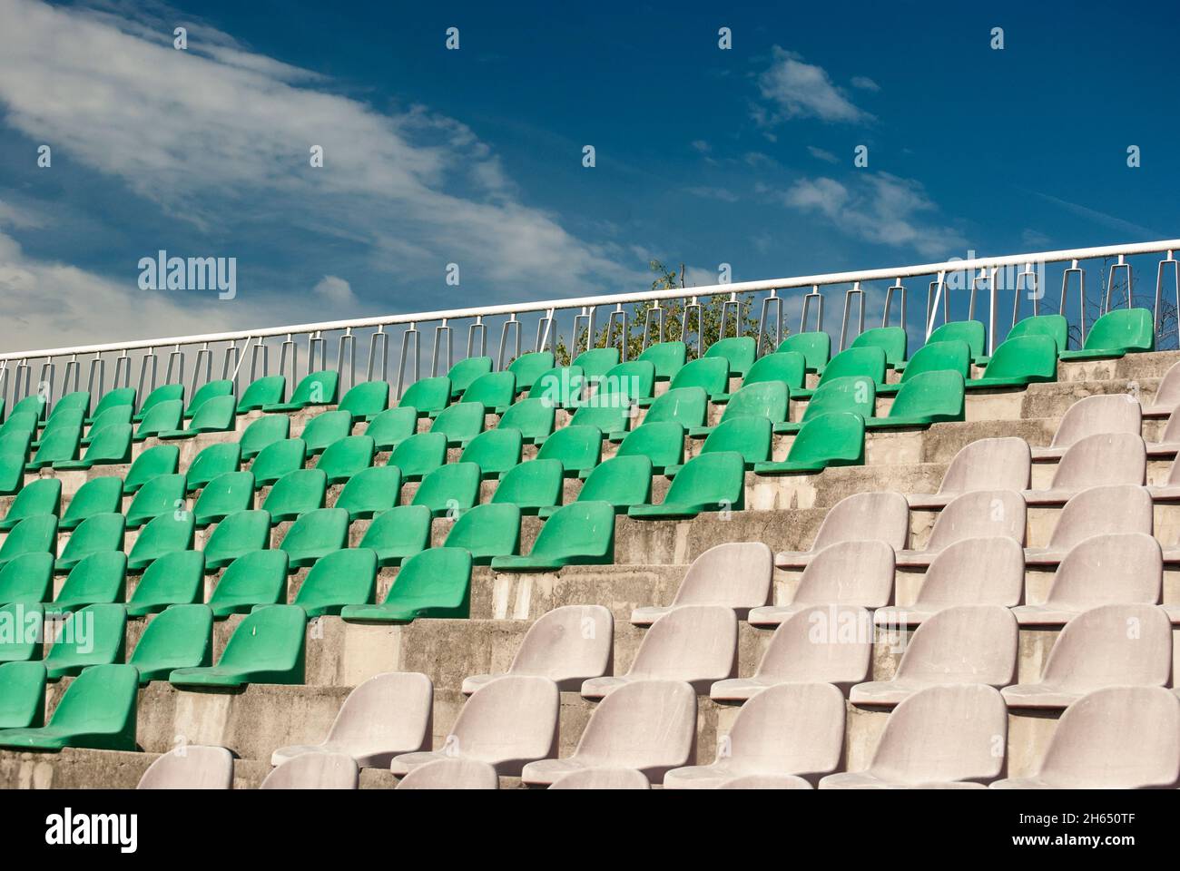 Gli spettatori in plastica verde vuoti si trovano a primo piano sul palco dello stadio di calcio Foto Stock