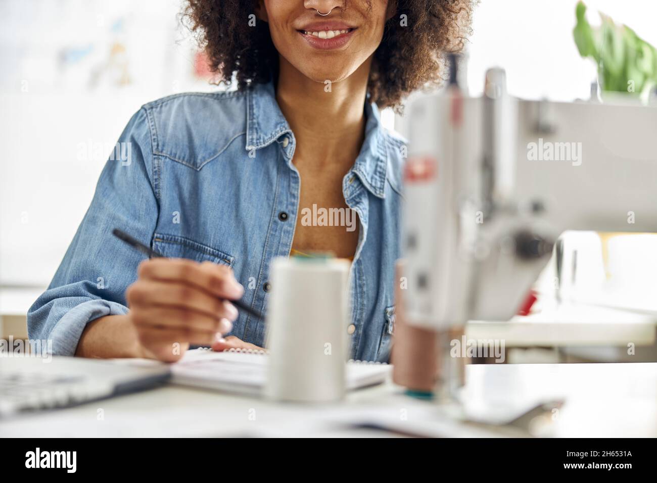 Stilista afro-americano di moda donna disegna modello di abbigliamento sul posto di lavoro in studio luce primo piano Foto Stock