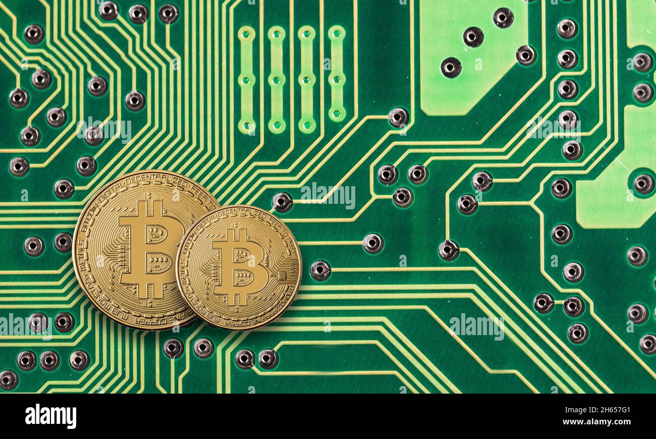 Moneta d'oro Bitcoin sul circuito stampato verde del computer Foto Stock