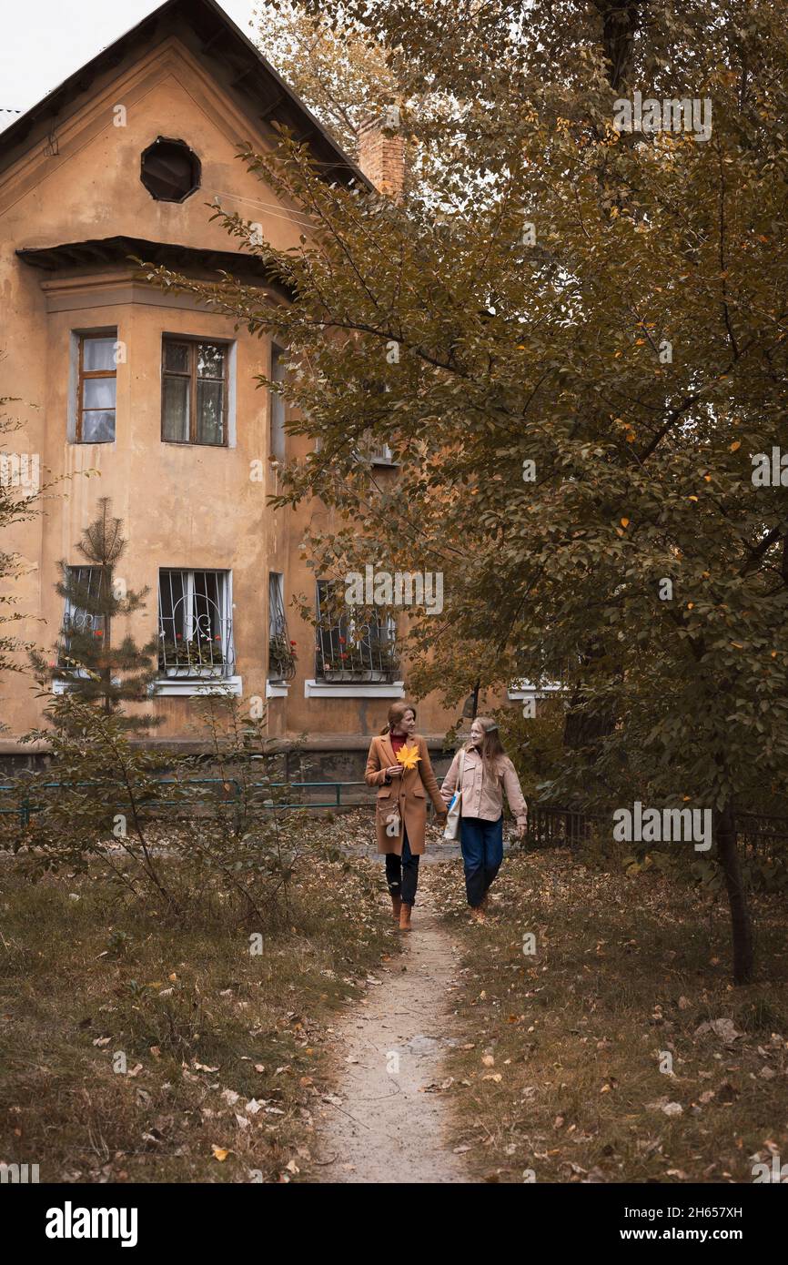 autunno in città, mamma e figlia stanno camminando per strada Foto Stock