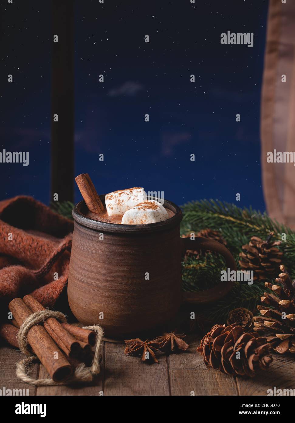 Tazza di cioccolata calda con marshmallow e cannella accanto a una finestra con il cielo notturno stary sullo sfondo Foto Stock
