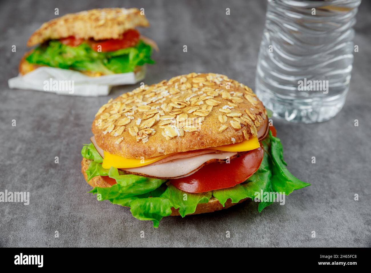 Sandwich a grani interi con prosciutto, formaggio, pomodori e lattuga. Foto Stock