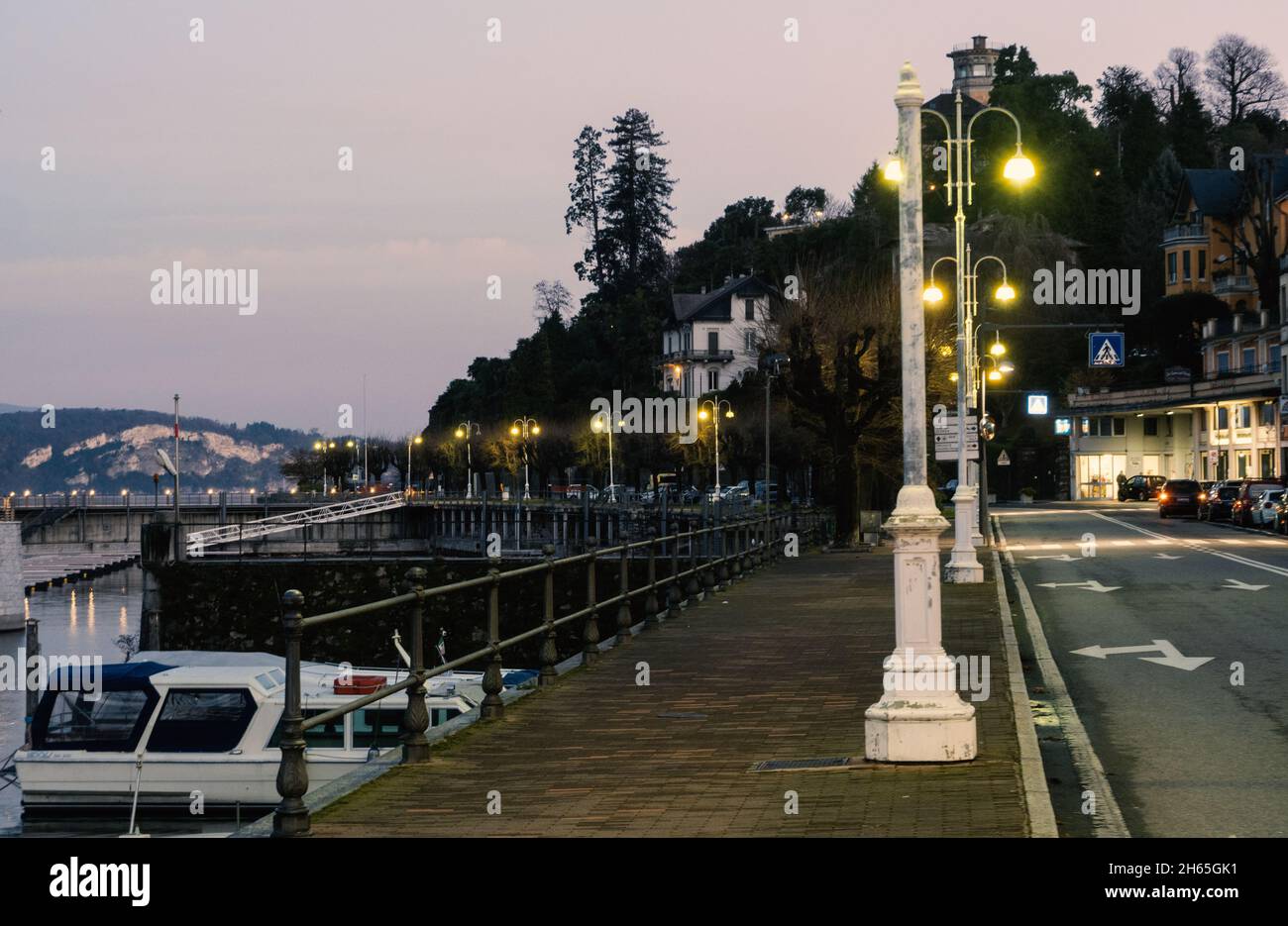 Alba sul deserte lungolago. Strada Simplon a Stresa illuminata da lampioni. Lago maggiore, Italia. Foto Stock