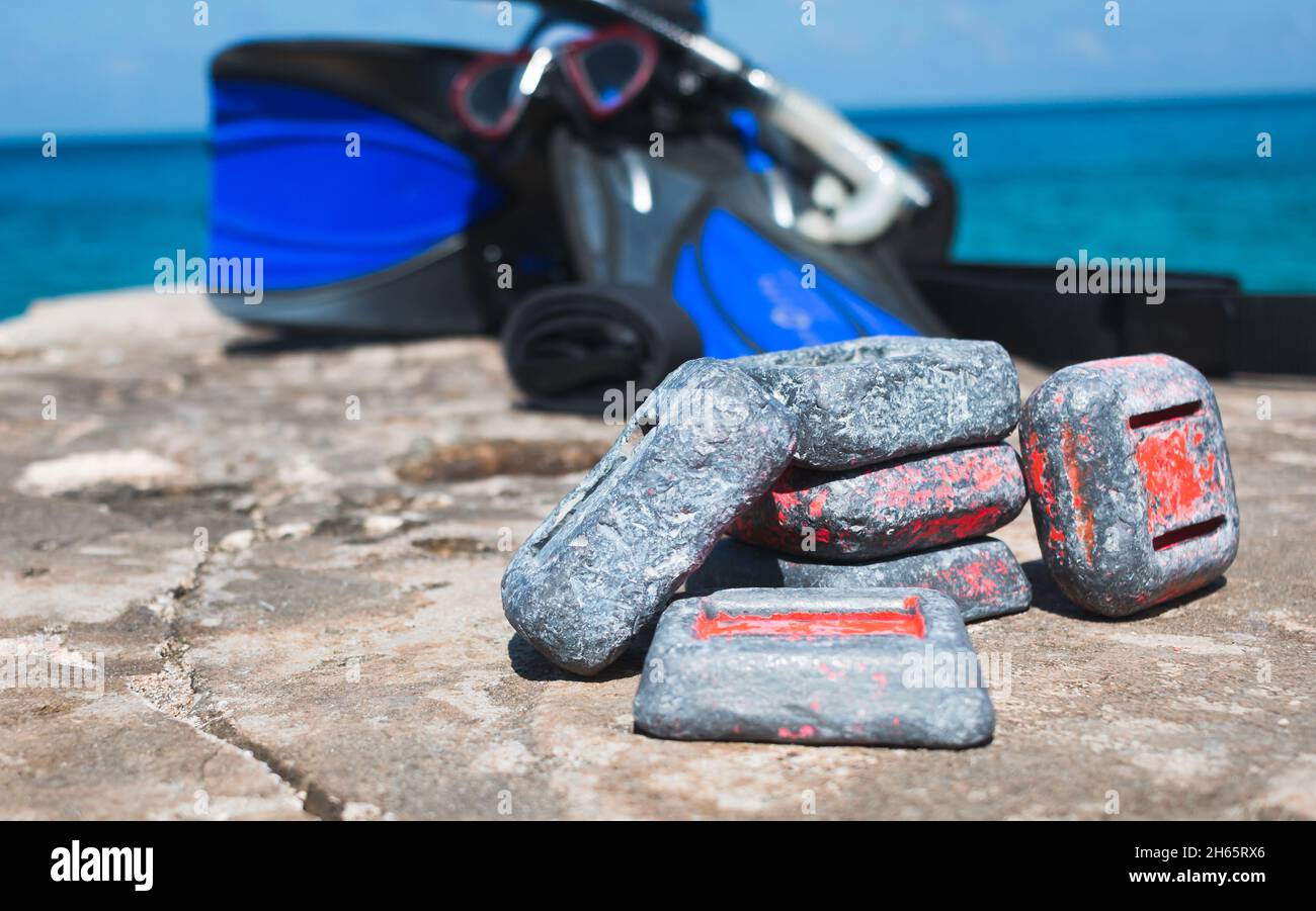 Pesi per immersioni subacquee su roccia vicino all'oceano con attrezzatura da snorkeling in background Foto Stock
