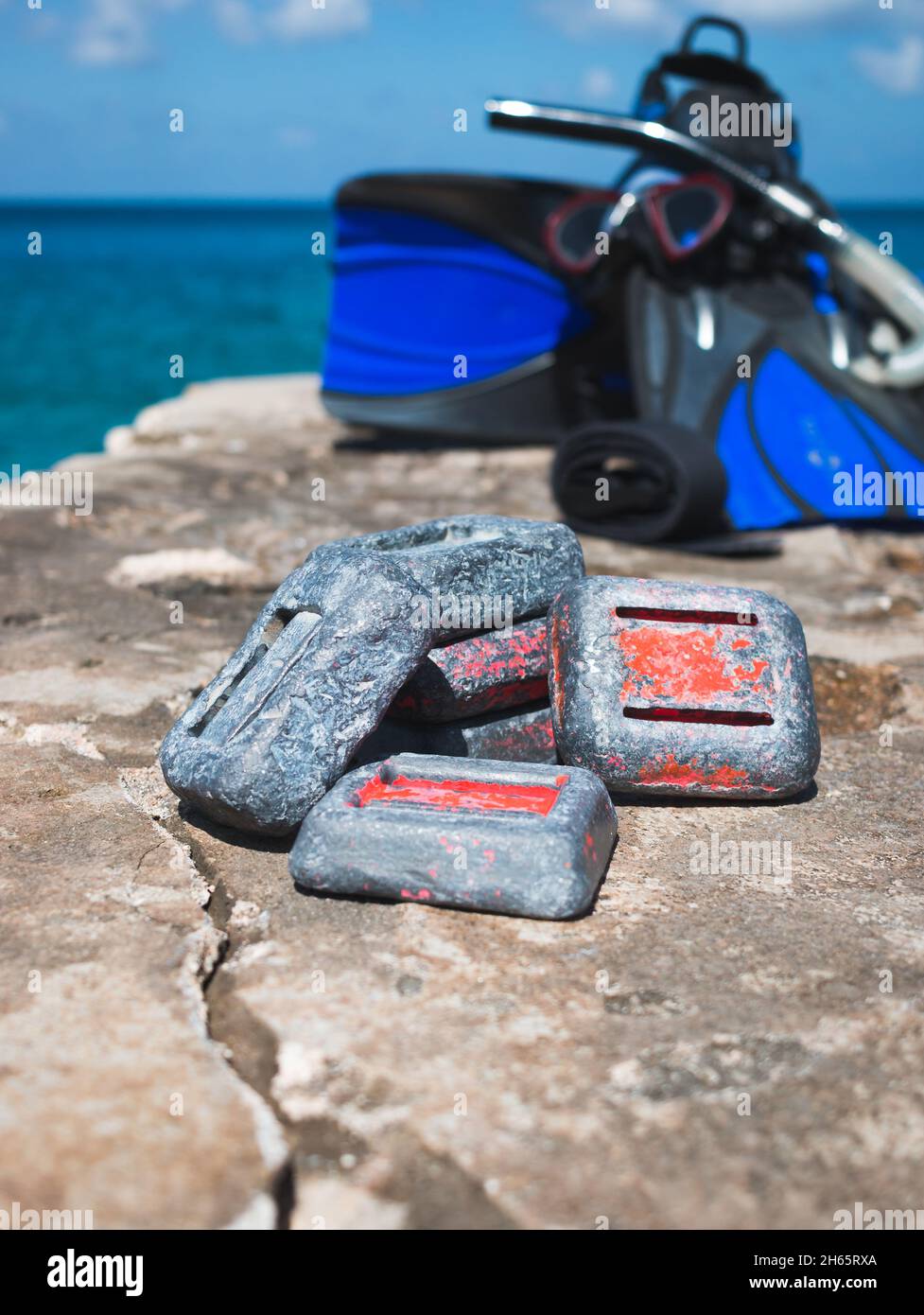 Pesi per immersioni subacquee su roccia vicino all'oceano con attrezzatura da snorkeling in background Foto Stock