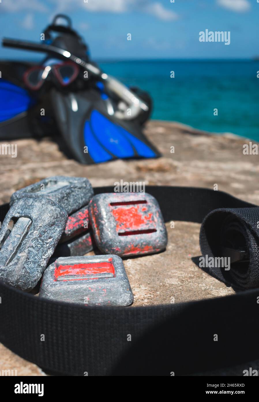 Pesi per immersioni subacquee su roccia vicino all'oceano con attrezzatura da snorkeling in background Foto Stock