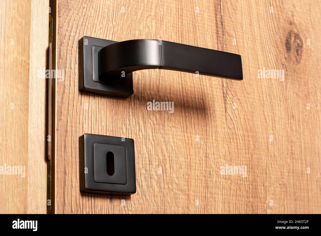 Maniglia interna della portiera ravvicinata. Porta in legno con maniglia nera Foto Stock