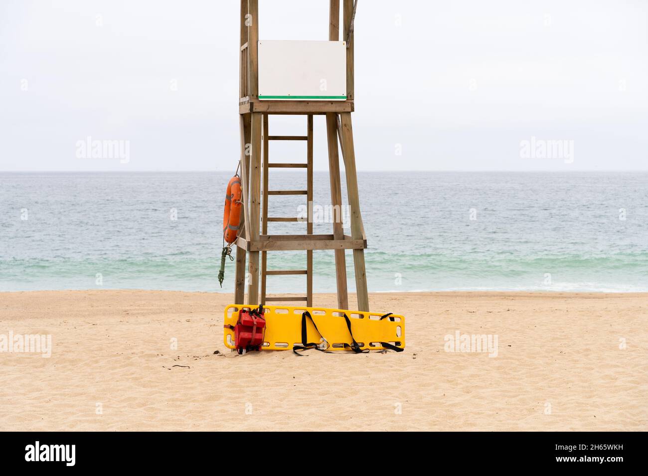 Backboard medico giallo e anello vita sulla torre di bagnino in legno sulla spiaggia vuota in Algarrobo, Cile Foto Stock