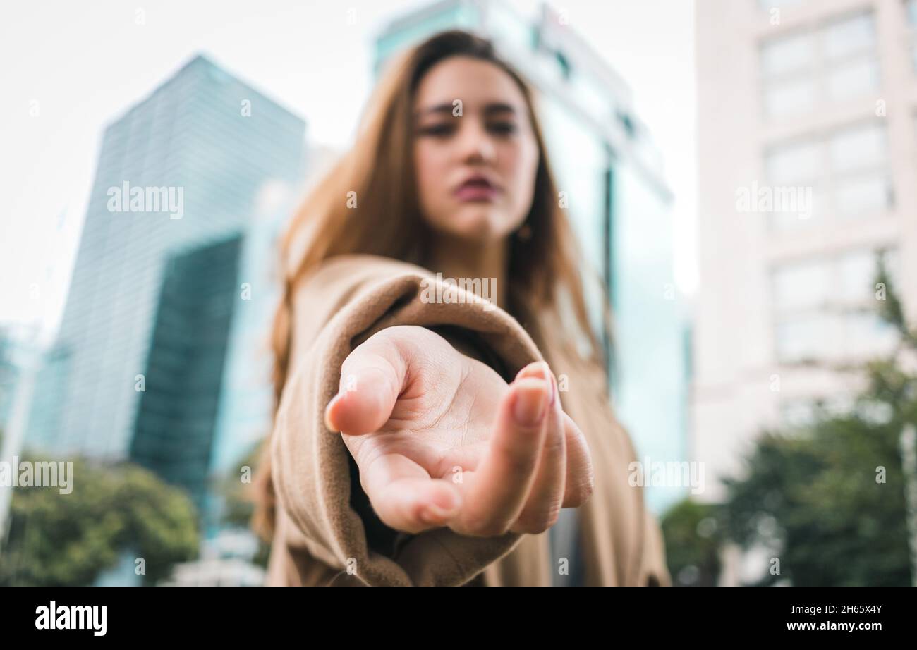 Elegante giovane donna modello adulto si pone di fronte alla costruzione con vento nei suoi capelli Foto Stock