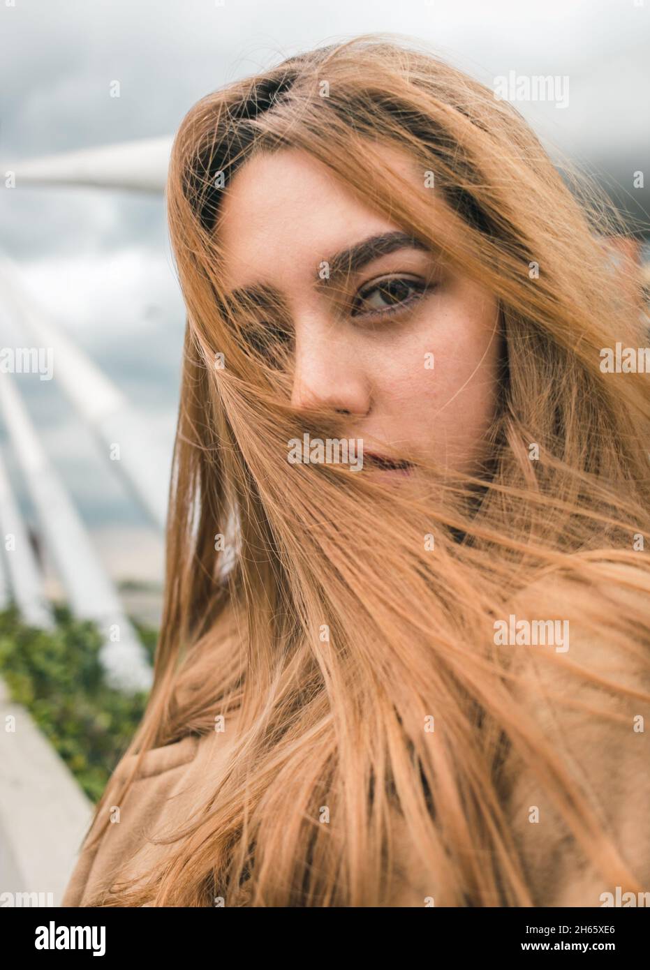 Bella donna colombiana si siede e si pone in ambiente urbano - capelli d'oro rosso e linee guida Foto Stock