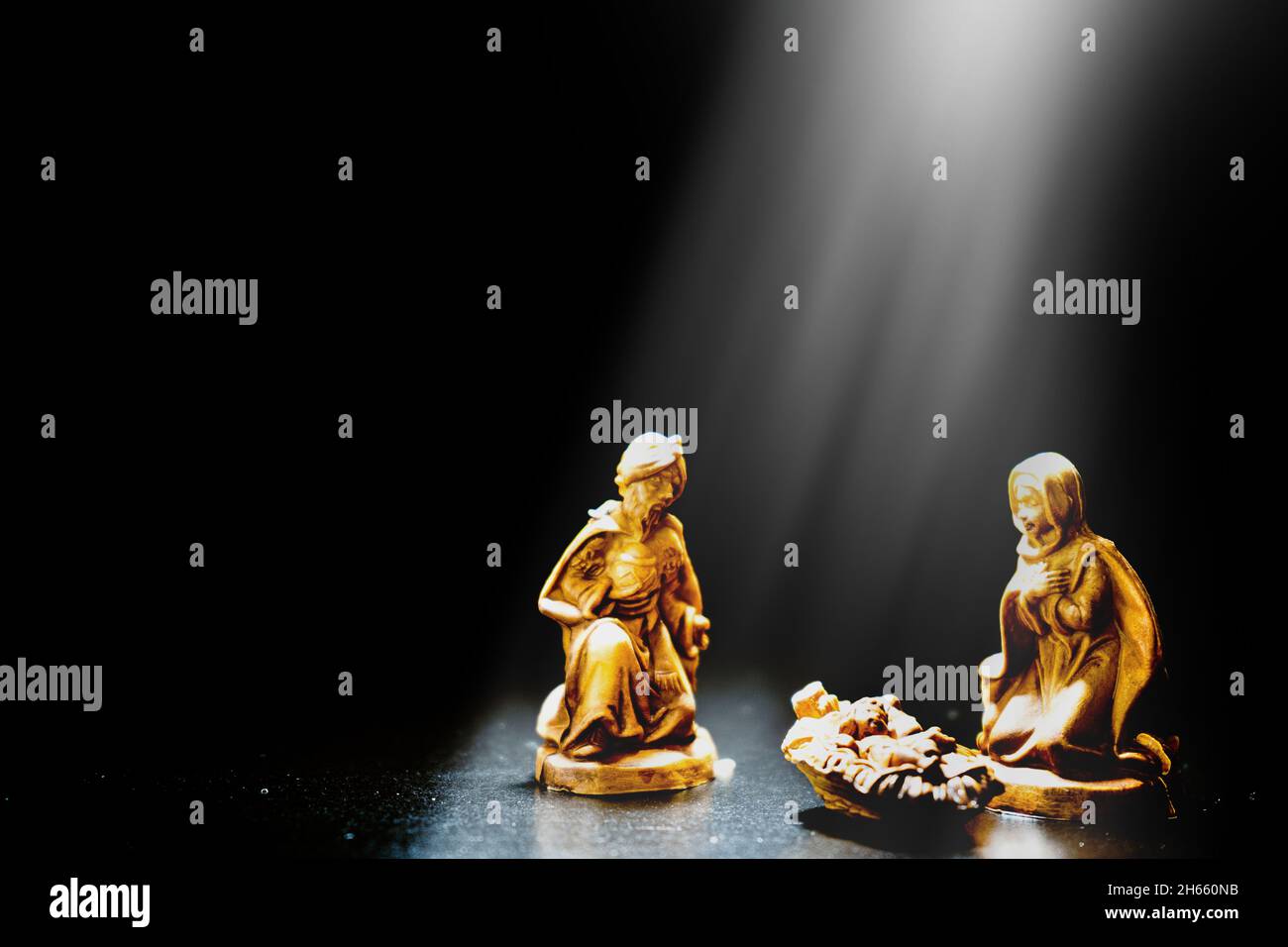 Un presepio di Natale illuminato con luce diretta sulle figure con sfondo nero e spazio per il testo. Foto Stock