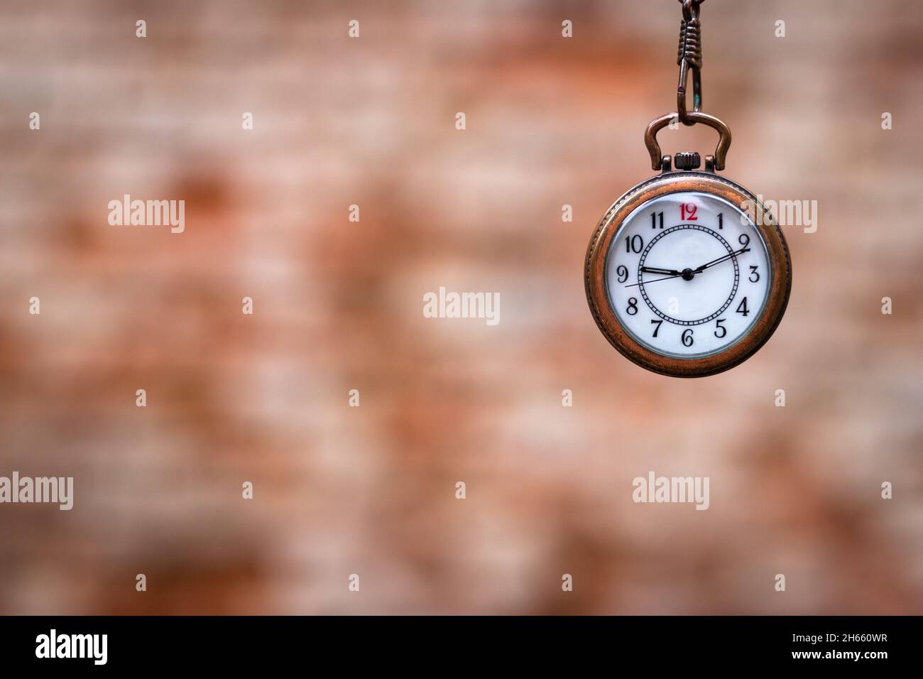 Orologio tascabile contro muro di mattoni sfocati. Concetto di tempo con spazio di copia. Orologio retrò. Messa a fuoco selettiva Foto Stock