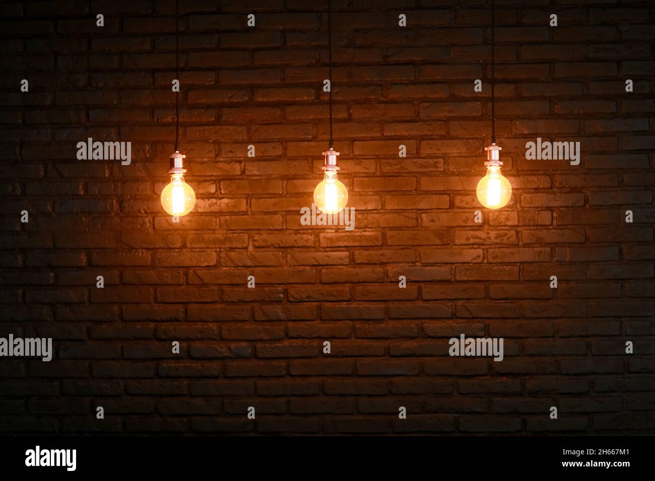 Tre lampade Edison contro un muro strutturato in mattoni. Foto Stock