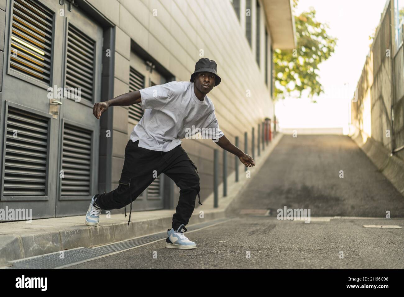 Giovane maschio nero fresco in un vestito stile strada ballando all'aperto Foto Stock