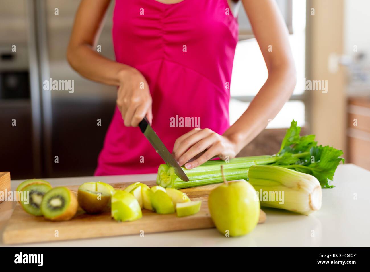 Metà della sezione della donna in casual chopping verdure da avocado sulla cucina isola a casa Foto Stock