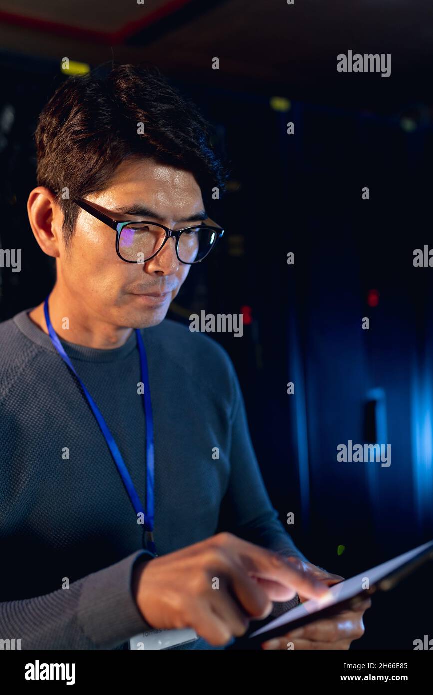 Ingegnere maschile asiatico che utilizza tablet digitale nella sala server del computer Foto Stock