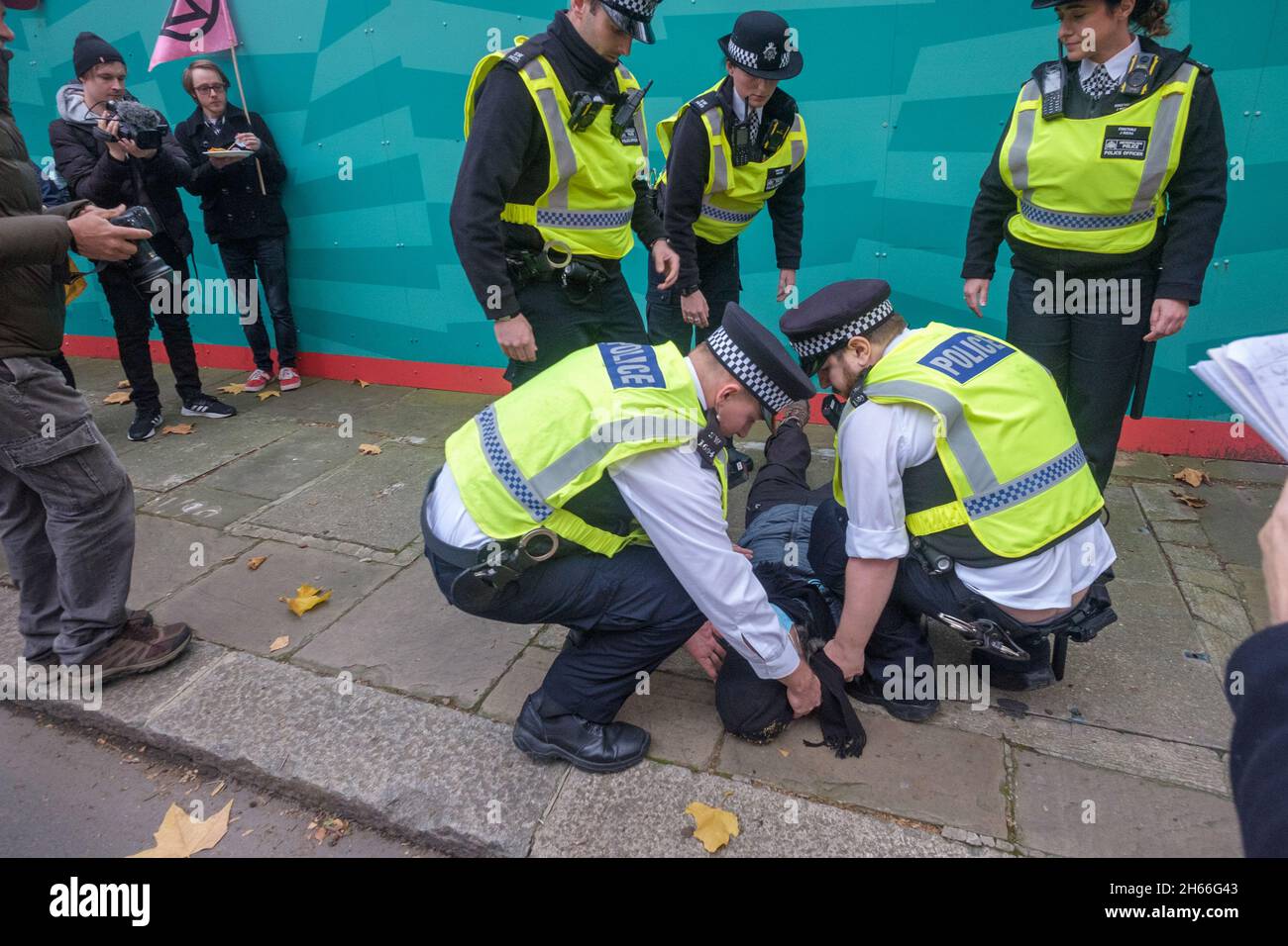 Londra, Regno Unito. 13 novembre 2021. La polizia ha deposto una careffully protesta sul marciapiede. Estinzione la ribellione si è comportata a Londra perché la COP26 non è riuscita ad adottare le misure necessarie per evitare la catastrofe climatica. Quando il Signore Sindaco tornò in città, si fermarono sulla strada protestando, con alcuni seduti per bloccarla. Essi sottolineano la colpa della City di Londra nel finanziare lo sfruttamento e i combustibili sporchi che hanno portato al problema. La polizia li ha costretti al lato della strada dove hanno continuato a protestare mentre la processione è passata. Peter Marshall/Alamy Live News Foto Stock