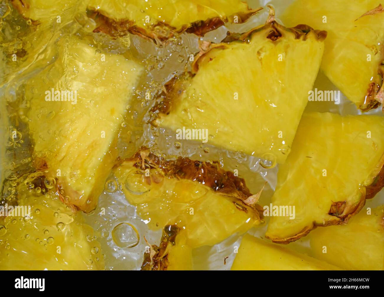Primo piano fette fresche di ananas giallo su sfondo bianco. Fette di ananas in acqua frizzante su sfondo bianco, primo piano. Immagine orizzontale. Foto Stock