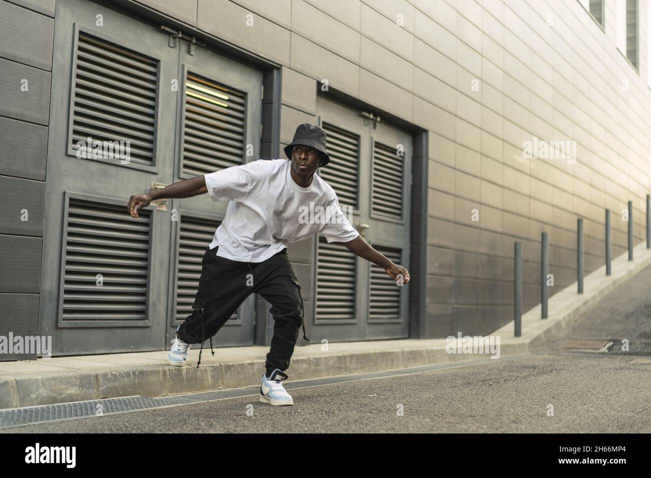 Giovane maschio nero fresco in un vestito stile strada ballando all'aperto Foto Stock
