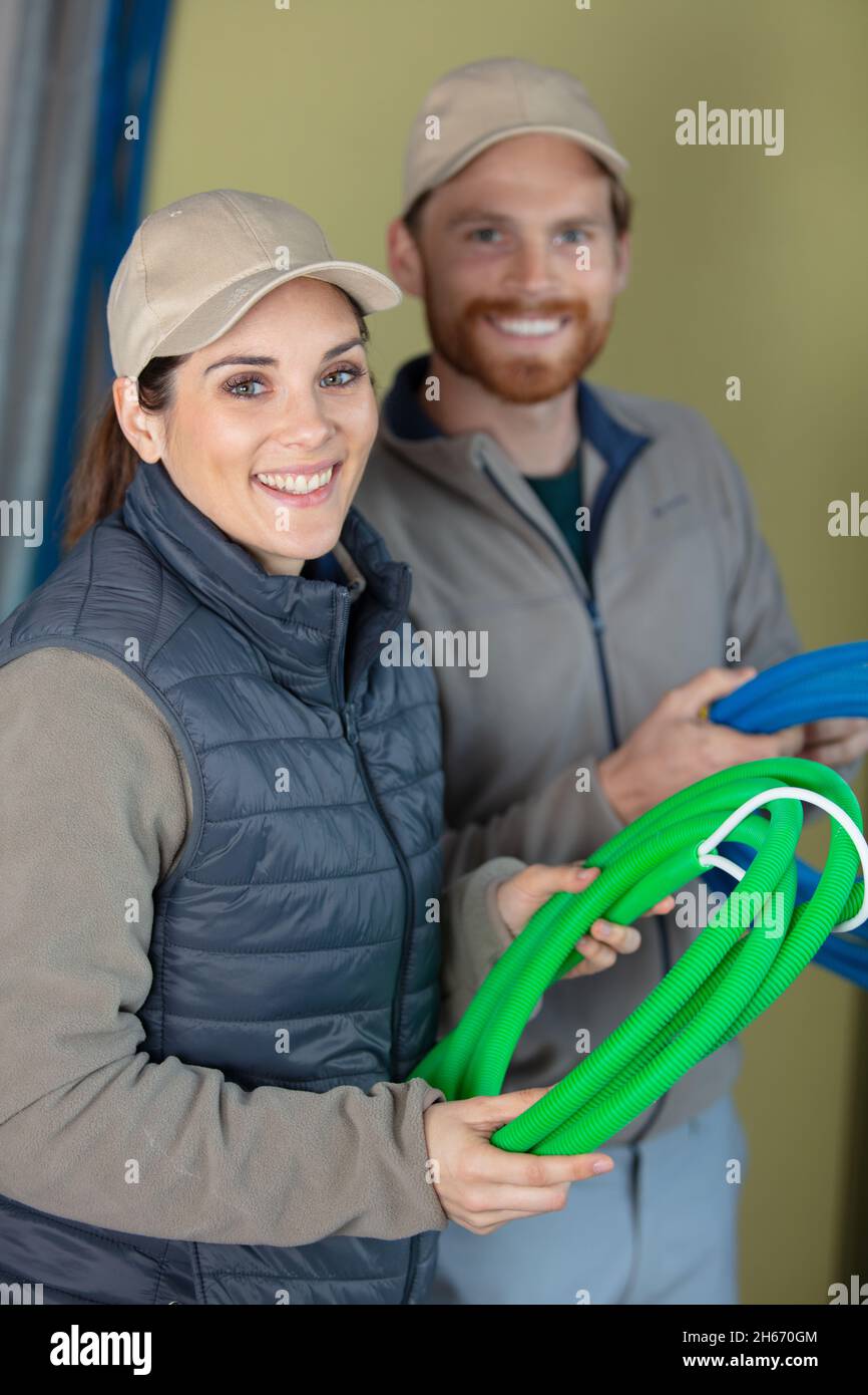 ritratto di lavoratori sorridenti che trasportano il tubo corrugato Foto Stock
