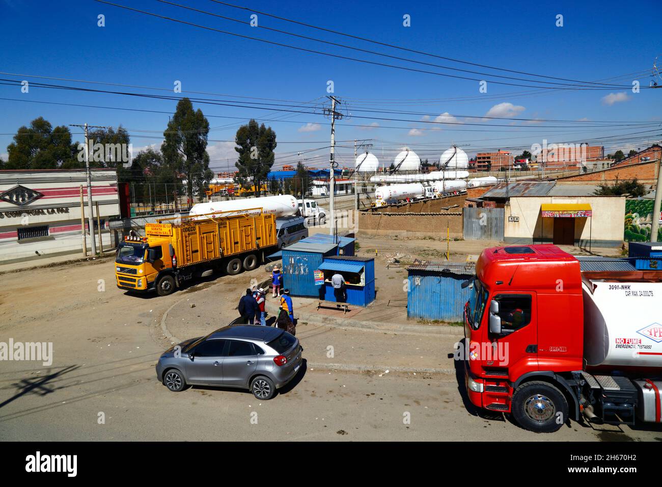 Senkata, El Alto, Bolivia. 13 novembre 2021. Autocarri con serbatoio di gas naturale liquido e un autocarro domestico per la fornitura di gas in bottiglia (giallo) all'esterno dell'impianto di carburante Senkata, in Av 6 de Marzo / Camino Oruro a El Alto. Yacimientos Petrolíferos Fiscales Bolivianos (YPFB, società petrolifera e di gas di proprietà statale della Bolivia) ha una grande raffineria e un grande impianto di stoccaggio, Che fornisce la Paz, El Alto e la zona circostante con benzina, diesel e gas naturale liquido (in bottiglie per uso domestico e anche per veicoli e altre industrie). Sullo sfondo sono alcuni dei serbatoi di stoccaggio di gas sferici. Foto Stock