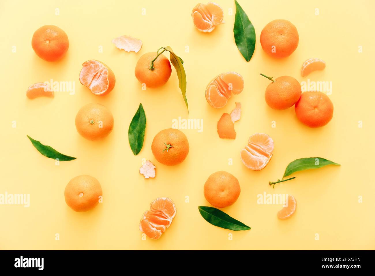 Clementine fresche con foglie su sfondo giallo, vista dall'alto Foto Stock