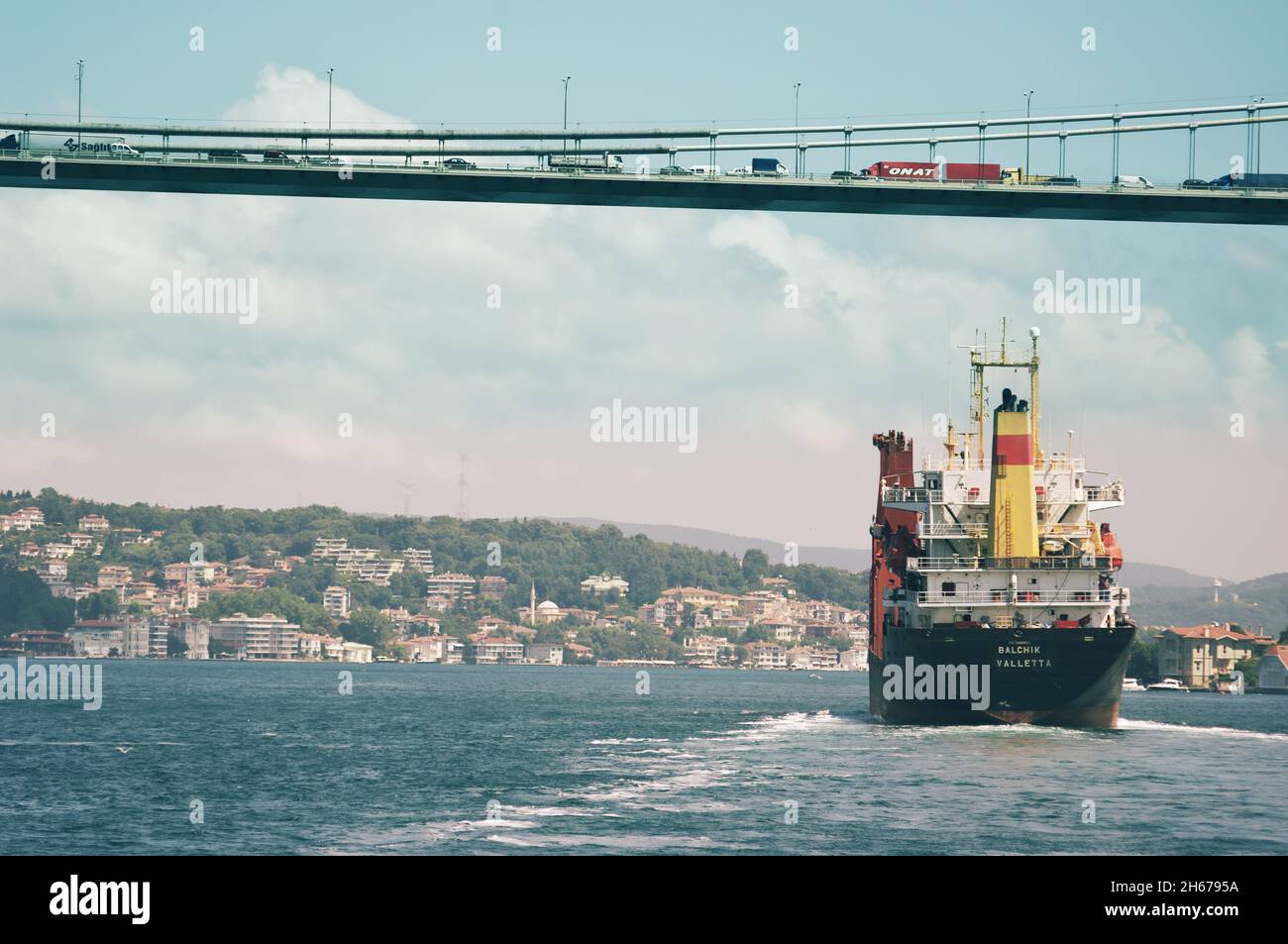 Scena urbana dello stretto del Bosforo con una nave da carico che attraversa il ponte occupato di veicoli in fila, la Turchia Foto Stock