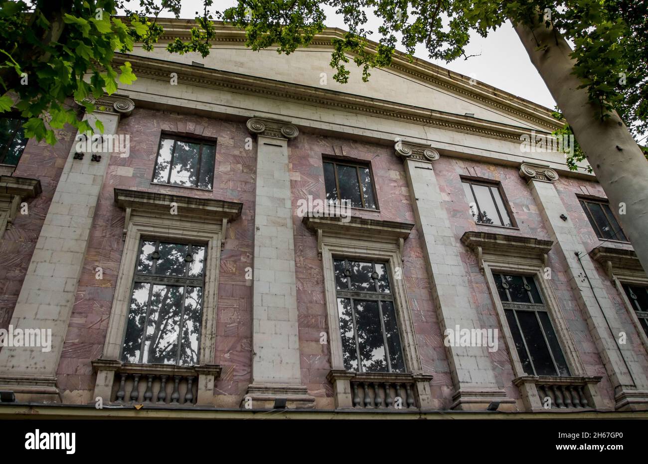 Lato anteriore della casa all'ombra di un albero con colonne piatte e finestre tra loro in via Rustaveli. Georgia, Tbilisi, 07.12.2014 Foto Stock