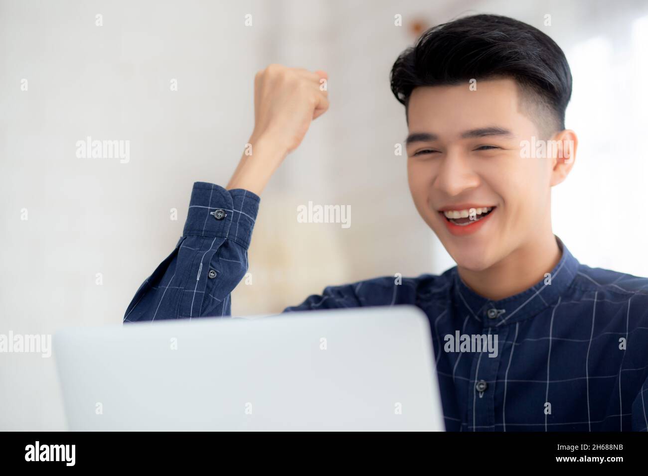 Felice giovane uomo d'affari lavoro su computer portatile finitura con entusiasmo e successo sulla scrivania a casa, uomo d'affari utilizzando notebook con successo e surp Foto Stock