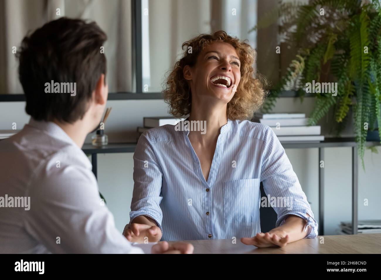 Giovane donna d'affari allegra che gode di piacevole conversazione con il collega. Foto Stock