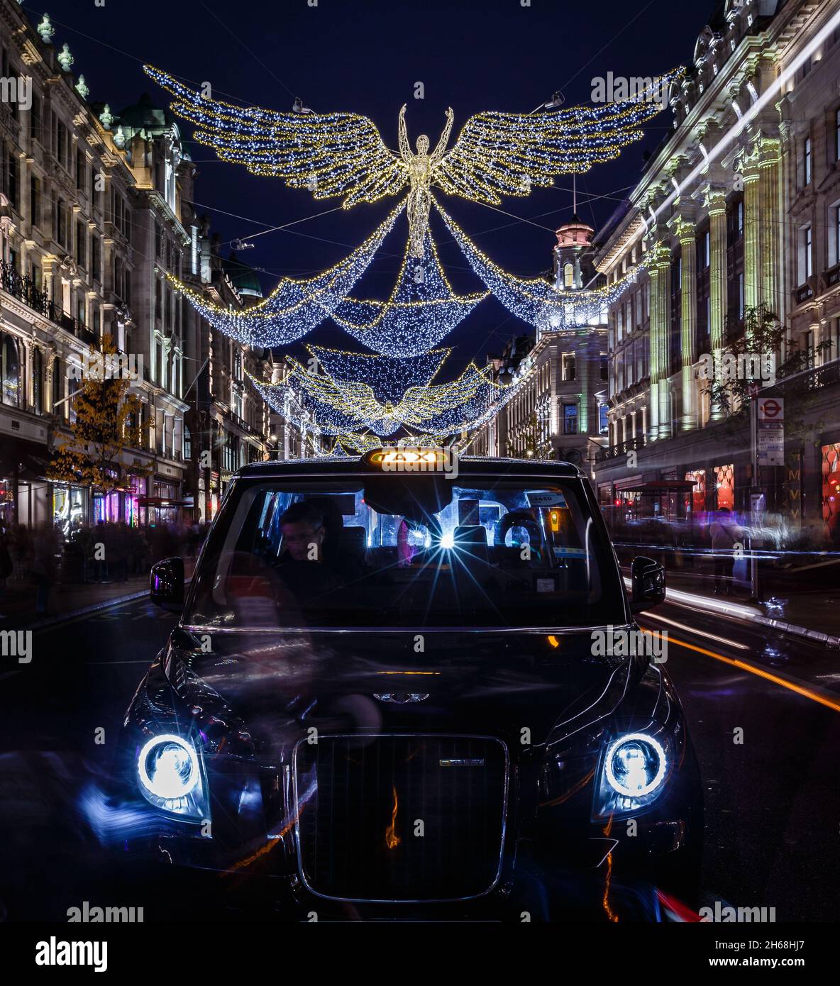 Un taxi attende una tariffa fuori da Hamley's su Regent Street sotto le luci di natale. Foto Stock