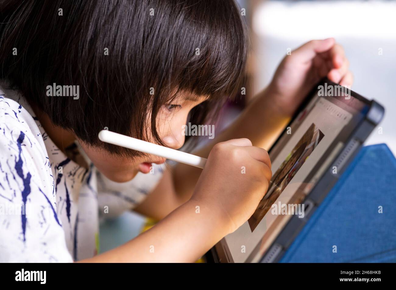 bambina che usa una penna digitale e che disegna sul touch screen pad del tablet con matita digitale per essere creativa e fare arte digitale e imparare a casa Foto Stock